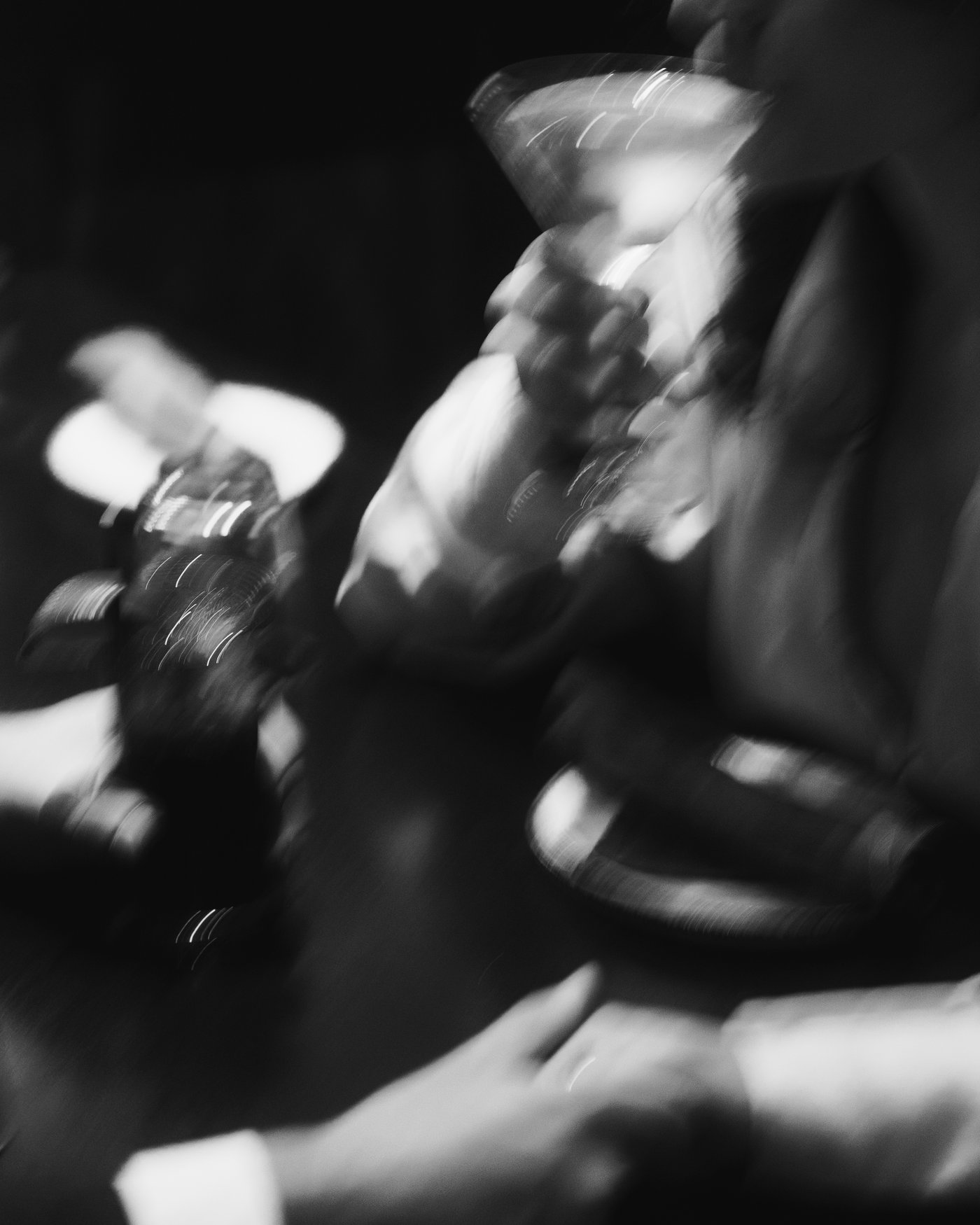 Black and white and deliberately smeared, hands and glasses dissolving into a long exposure