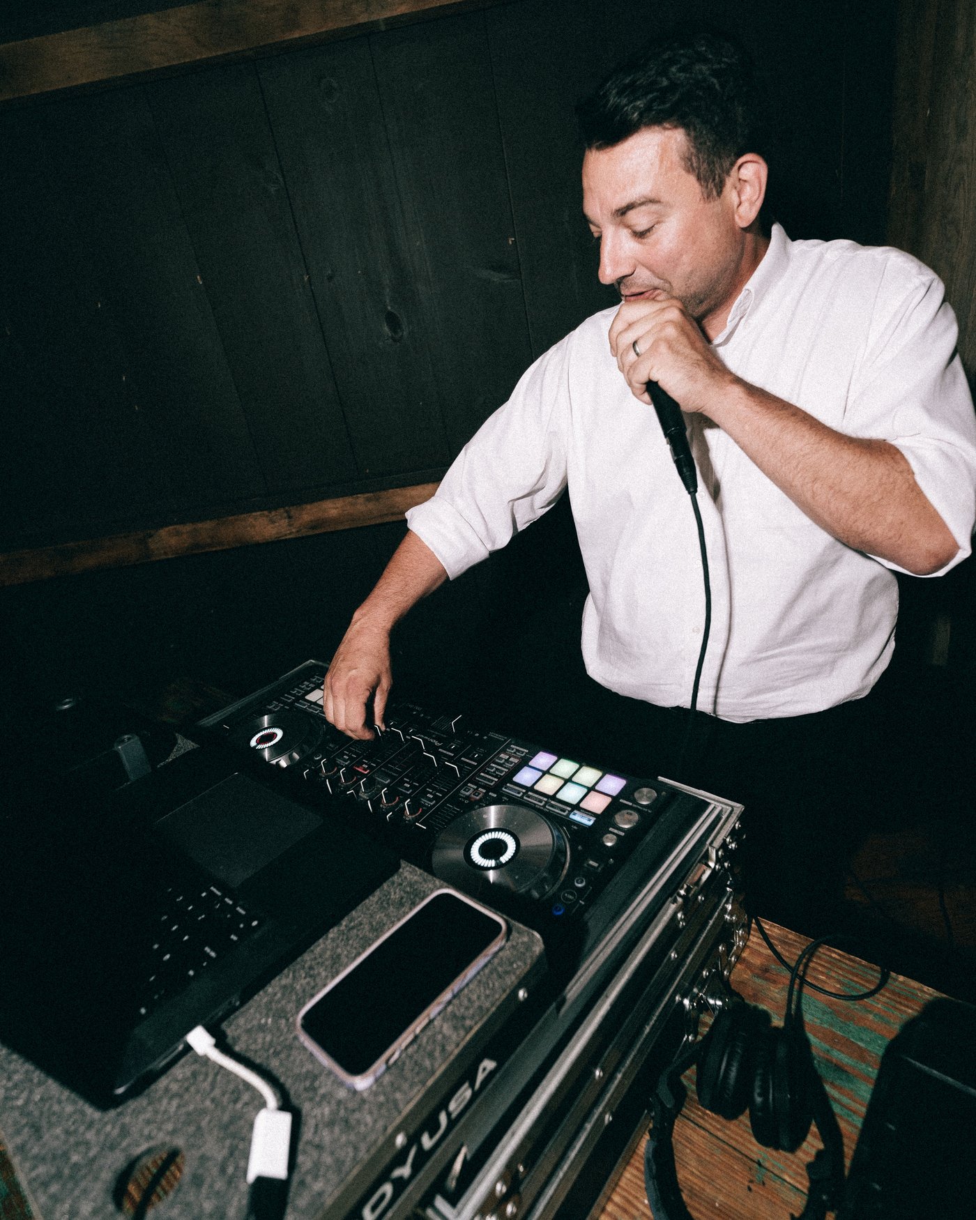 The DJ at the decks in the dark barn