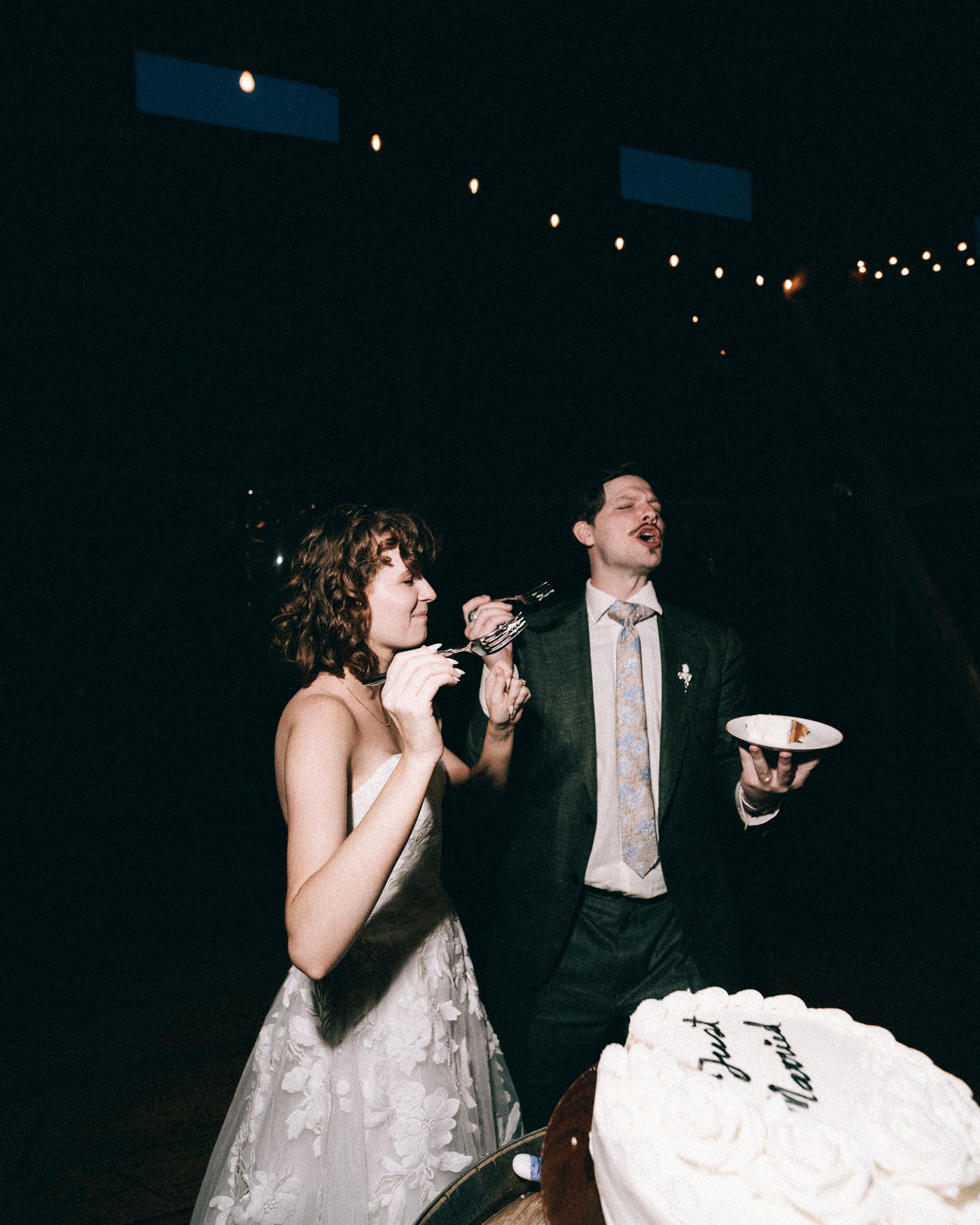 The bride and groom laughing over their plates of cake