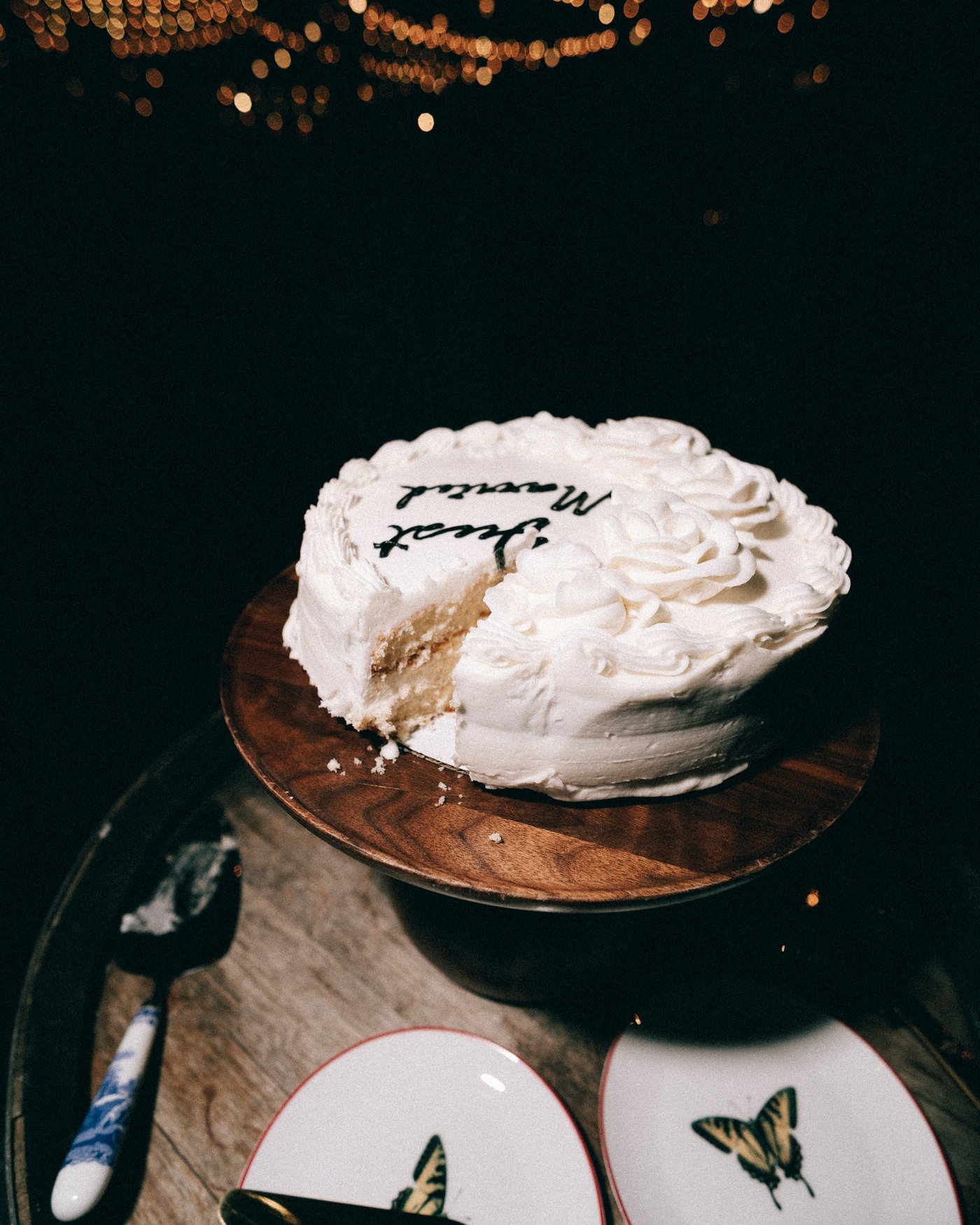 The single tier cake on its wooden stand, hand lettered across the top