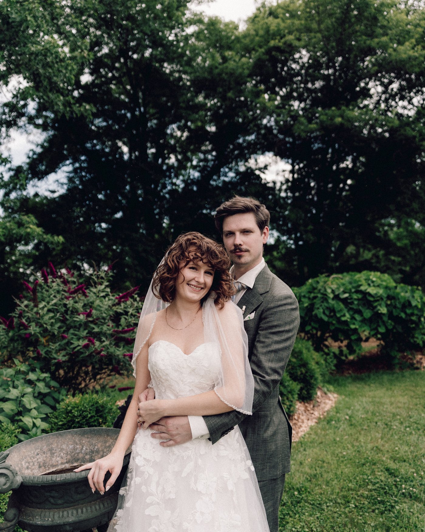 The bride and groom standing together in front of a large tree