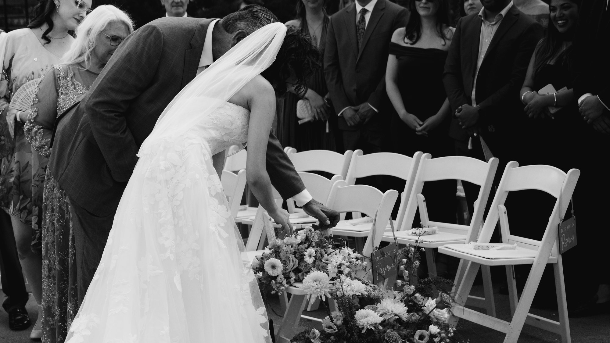 Black and white, a single empty chair with flowers laid on it, kept for the people who could not be there