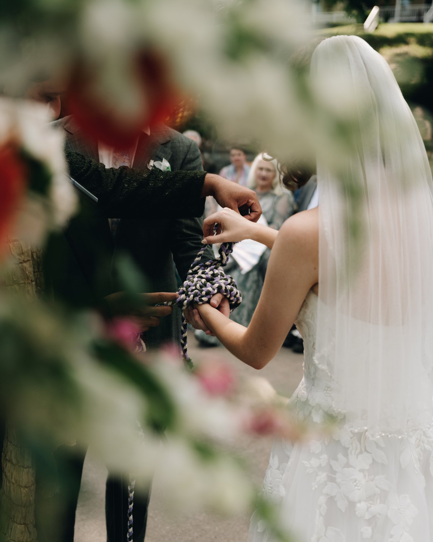 Flowers in the foreground with the couple soft behind them at the altar