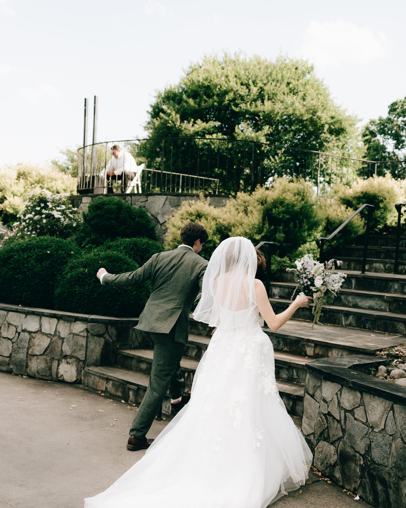 The couple climbing the stone steps up from the ceremony lawn