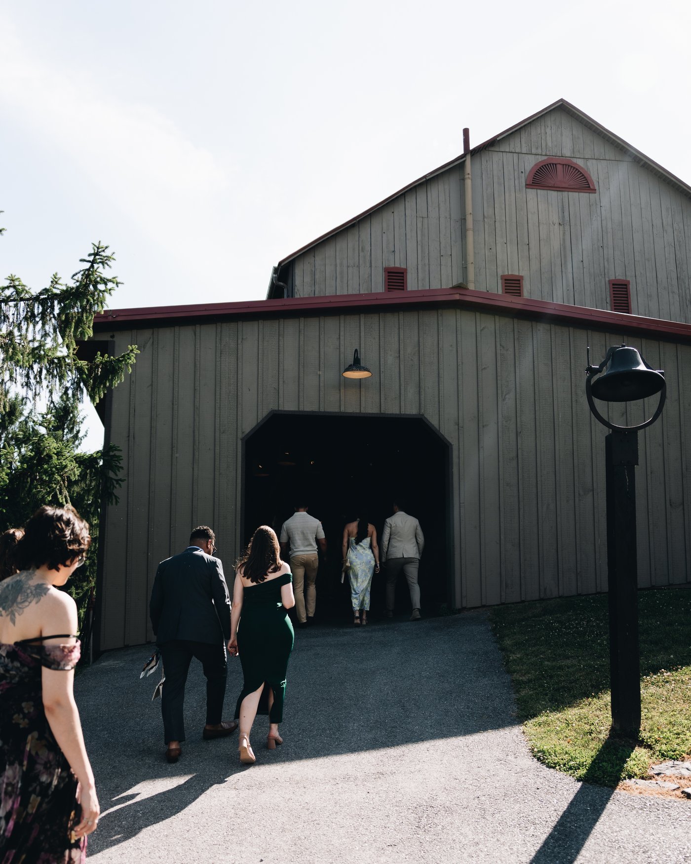 Guests walking into the lower side opening of the barn in the last of the daylight