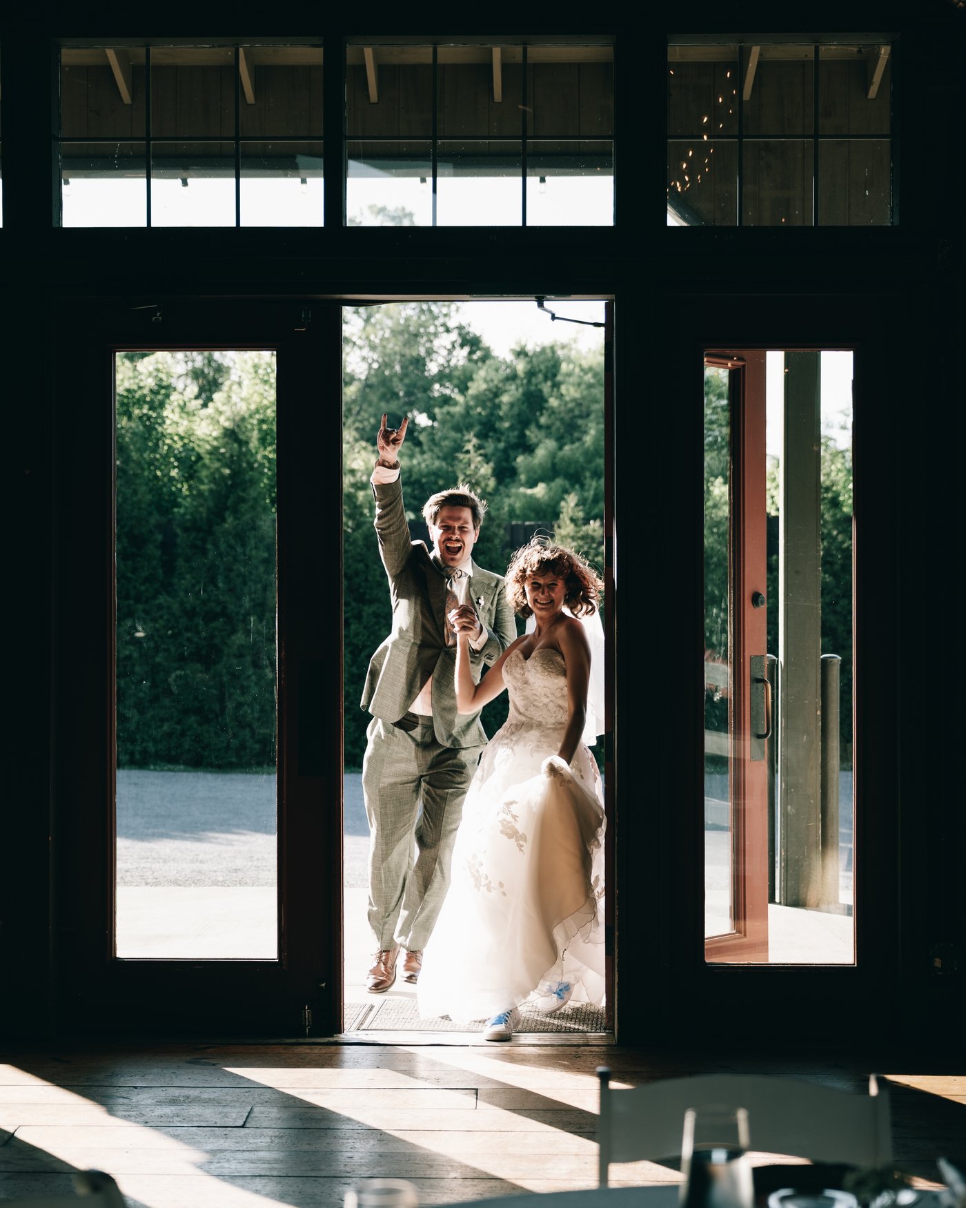 The bride and groom framed in the barn doorway with the daylight behind them