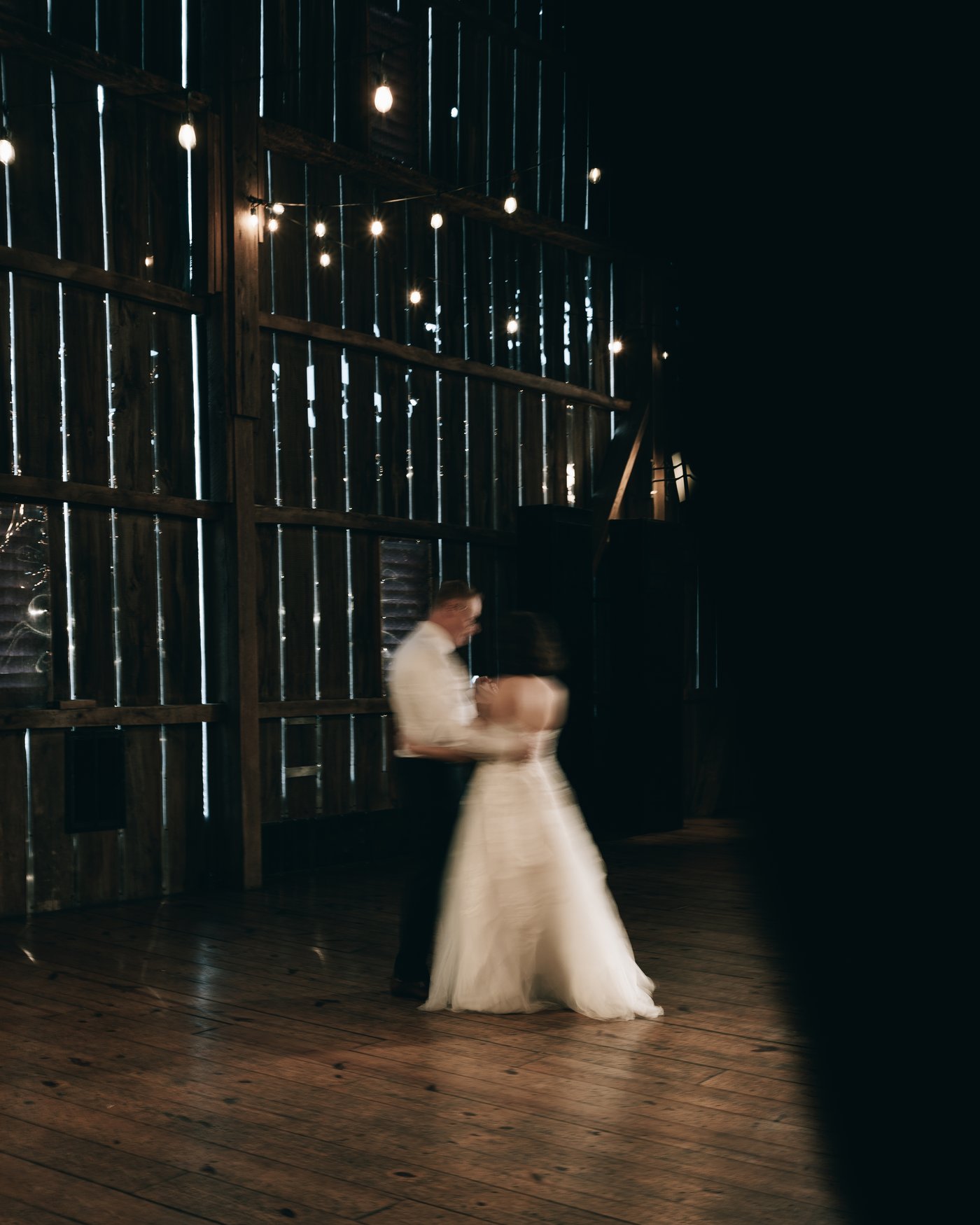 The couple dancing, blurred, under the string lights