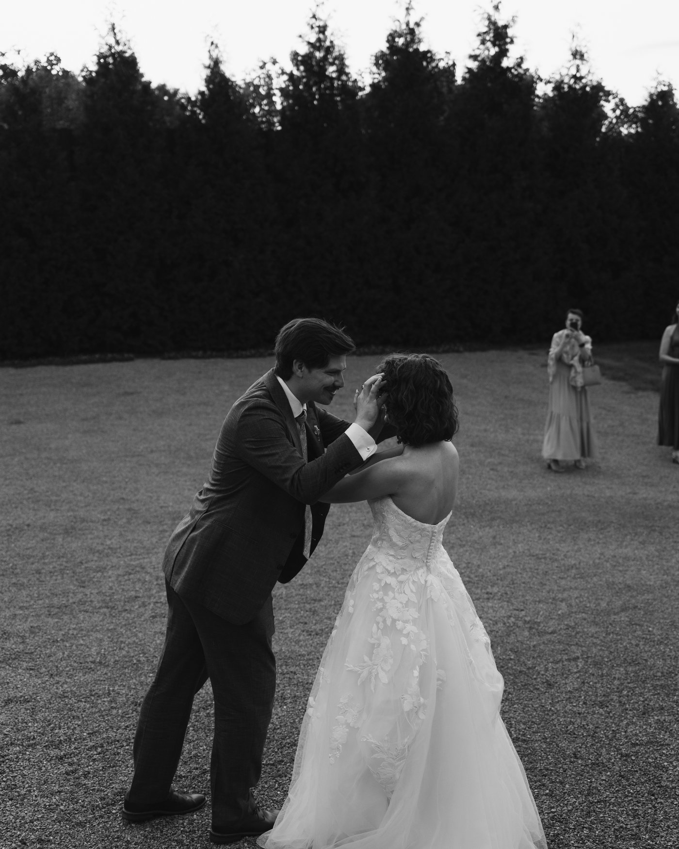 Black and white, the bride and groom dancing on the grass after dark