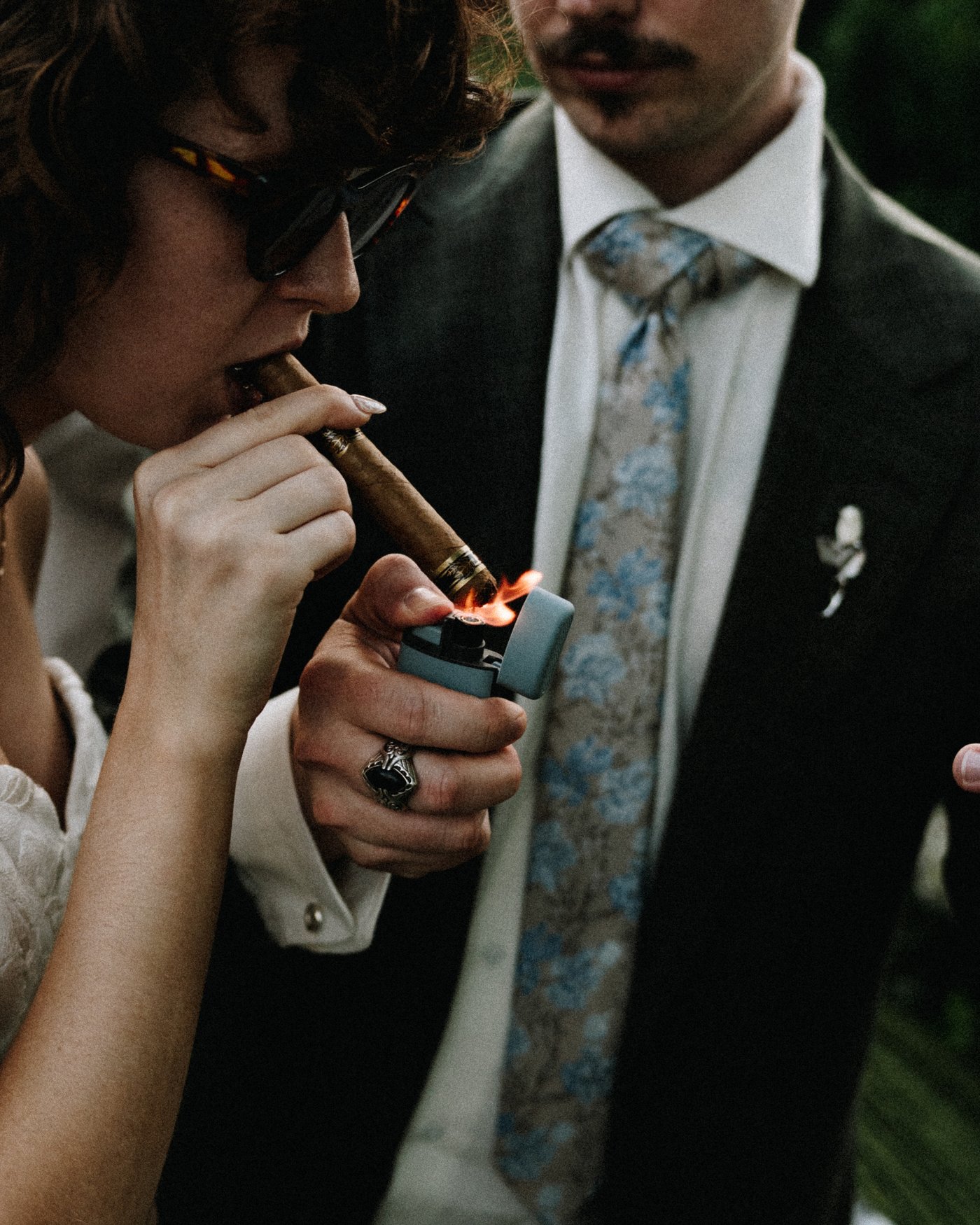 The groom lighting a cigar outside with his friends