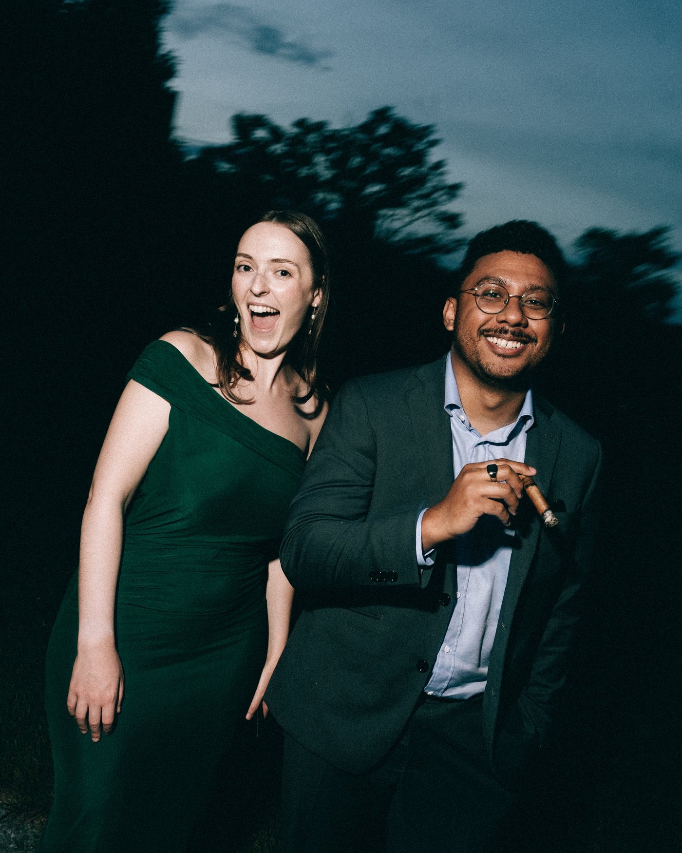 Guests laughing together outside, one of them holding a cigar