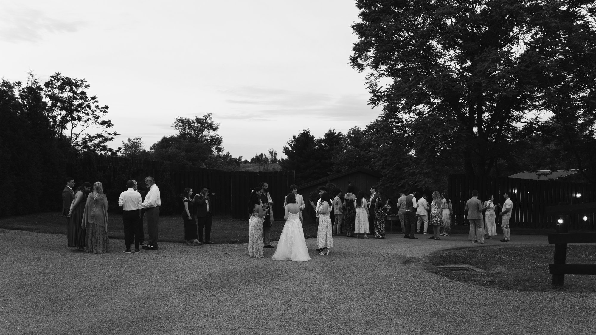 Black and white, the whole party gathered in a circle on the lawn at dusk