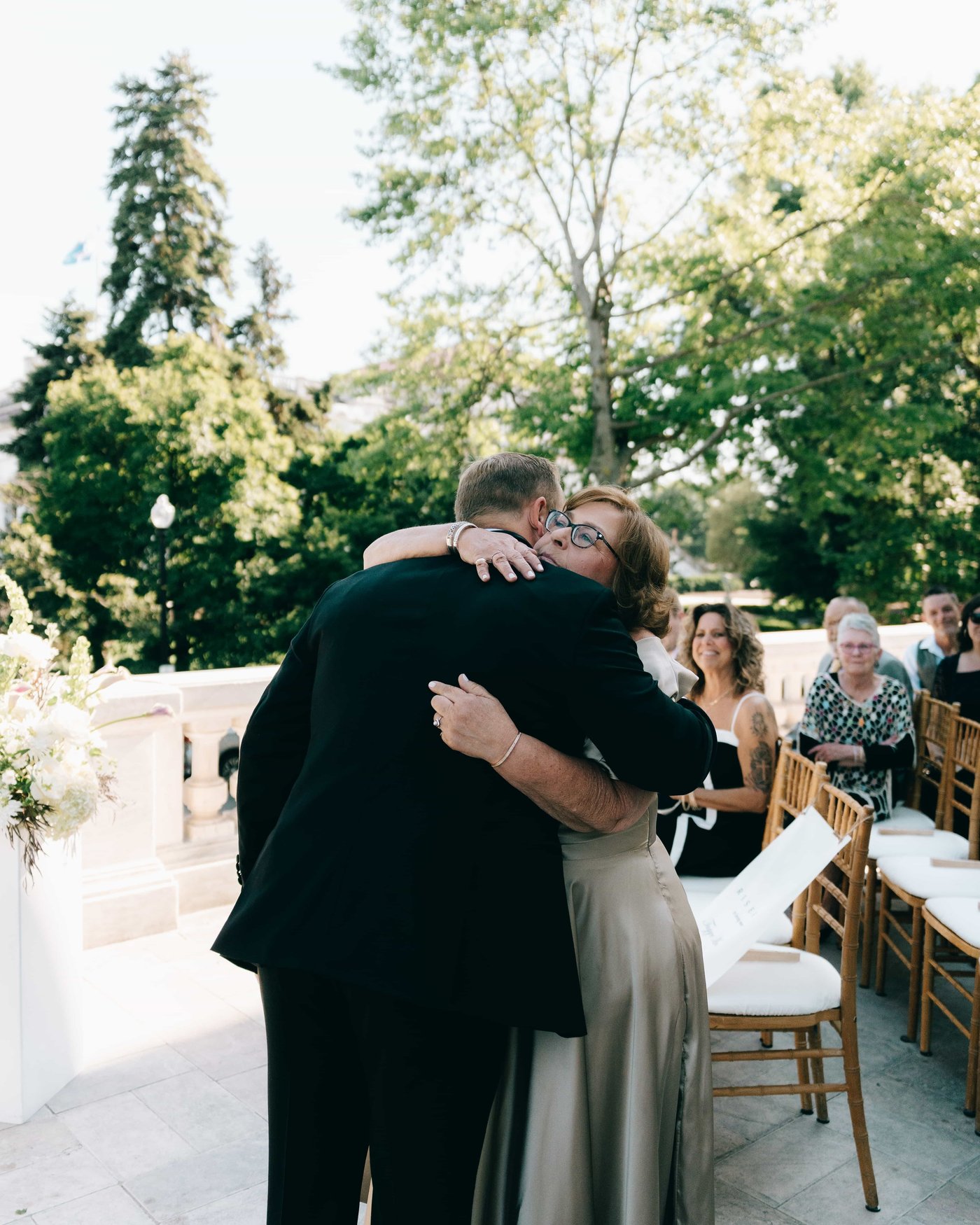 The groom pulled into a long hug at the front of the ceremony, guests smiling from their chairs