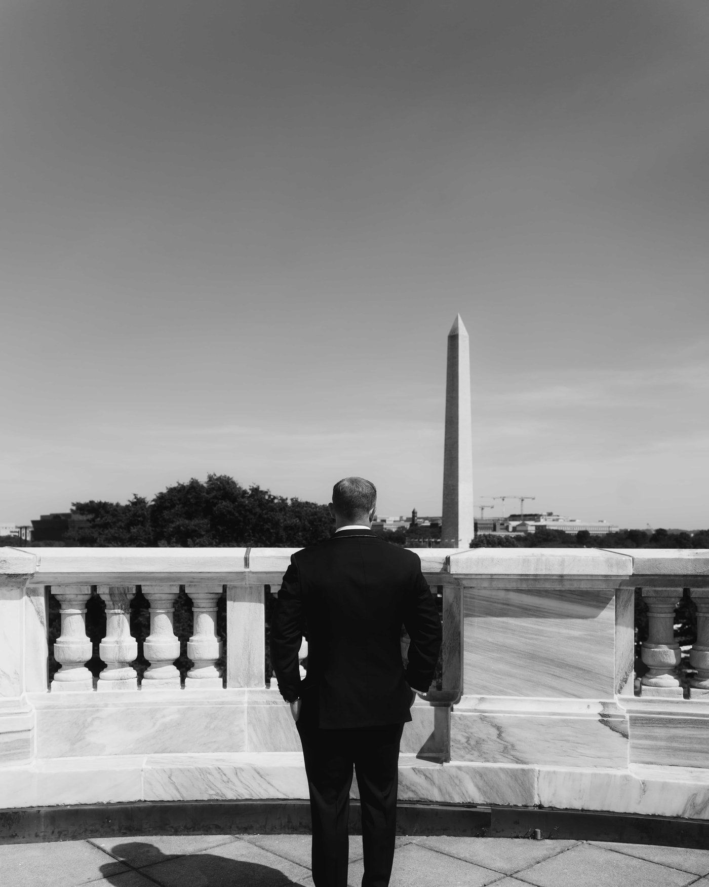 Black and white, the groom standing at the balustrade with his back turned, the Monument ahead of him