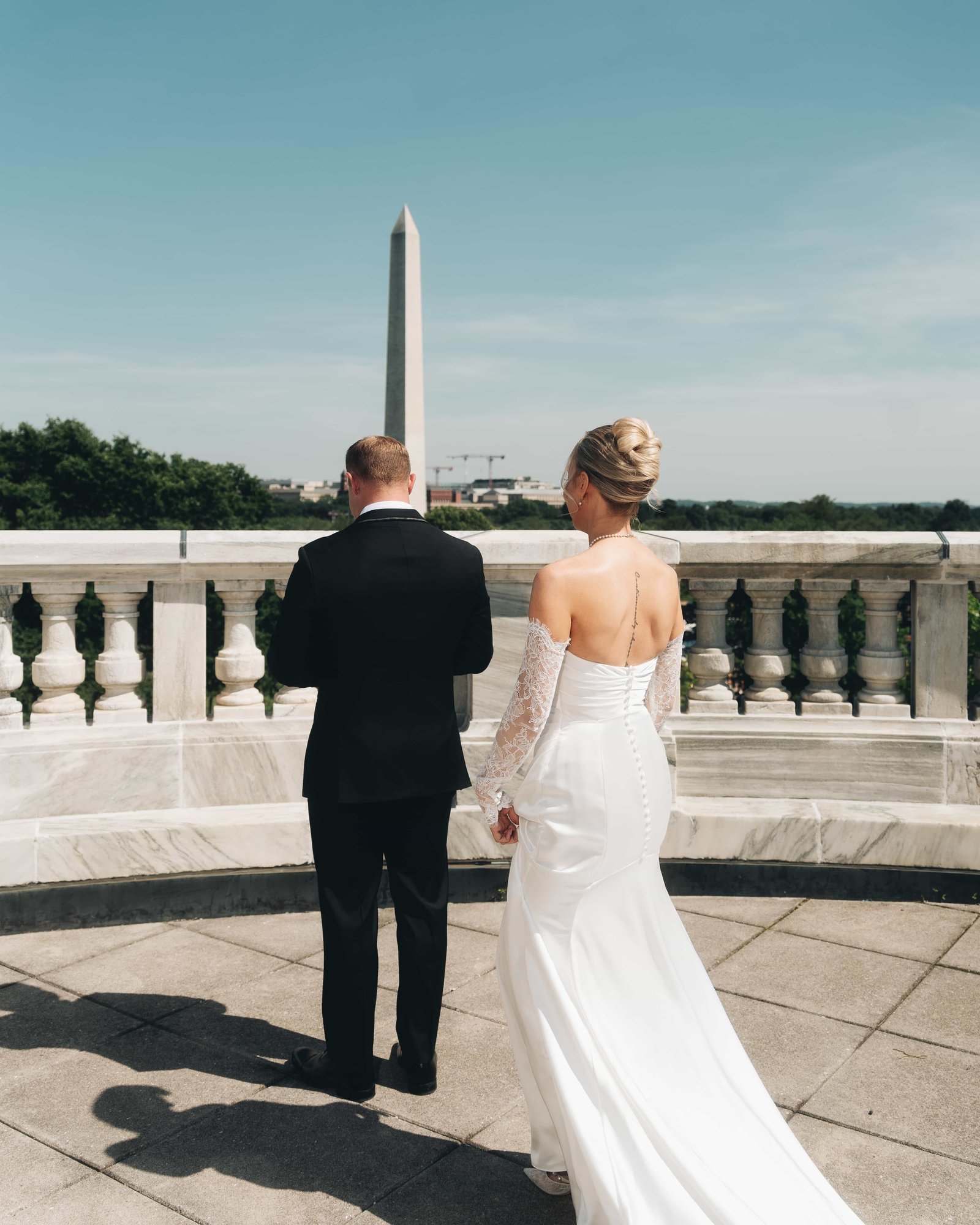 The bride stopped just behind the groom at the balustrade, the moment before he turns around