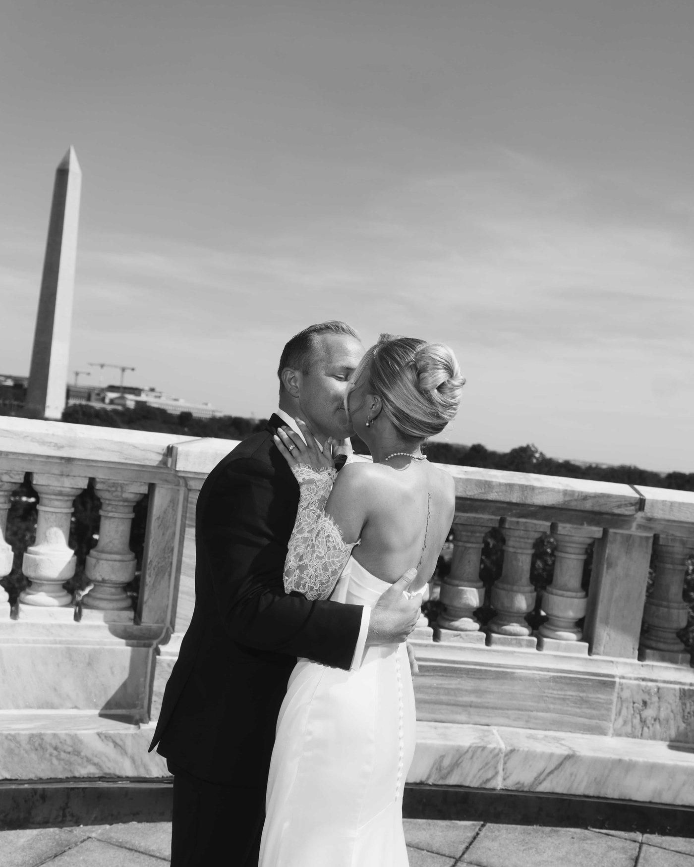Black and white, the couple kissing at the balustrade after the first look, the Monument over his shoulder