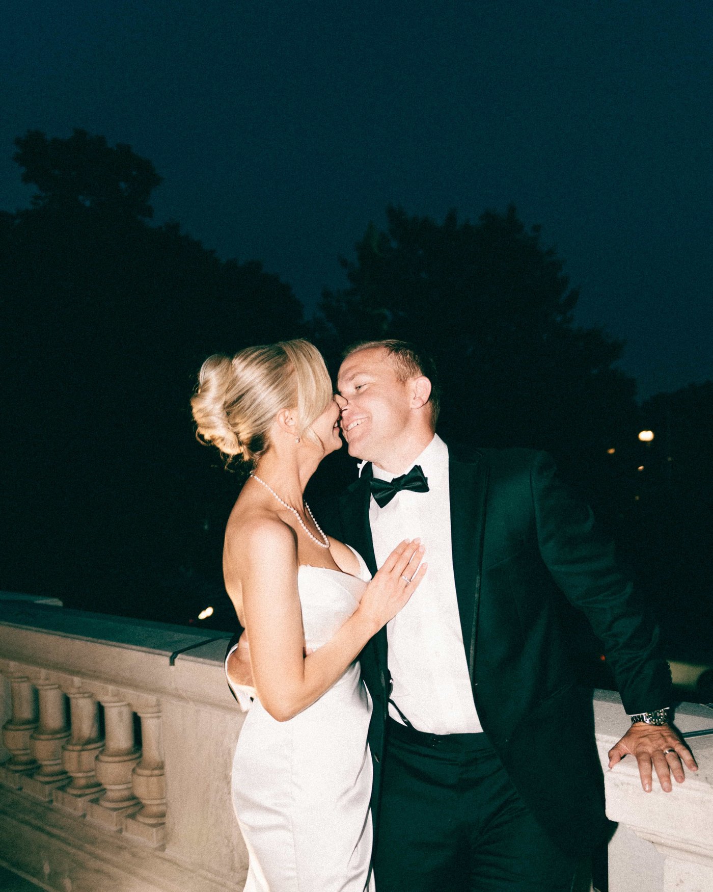 Nose to nose at the balustrade after dark, her hand resting flat on his chest