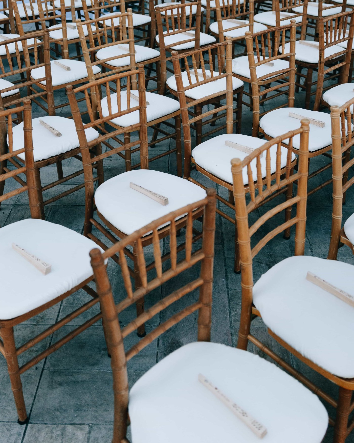 Rows of bamboo chairs waiting for the ceremony, a folded wooden fan laid on every white cushion