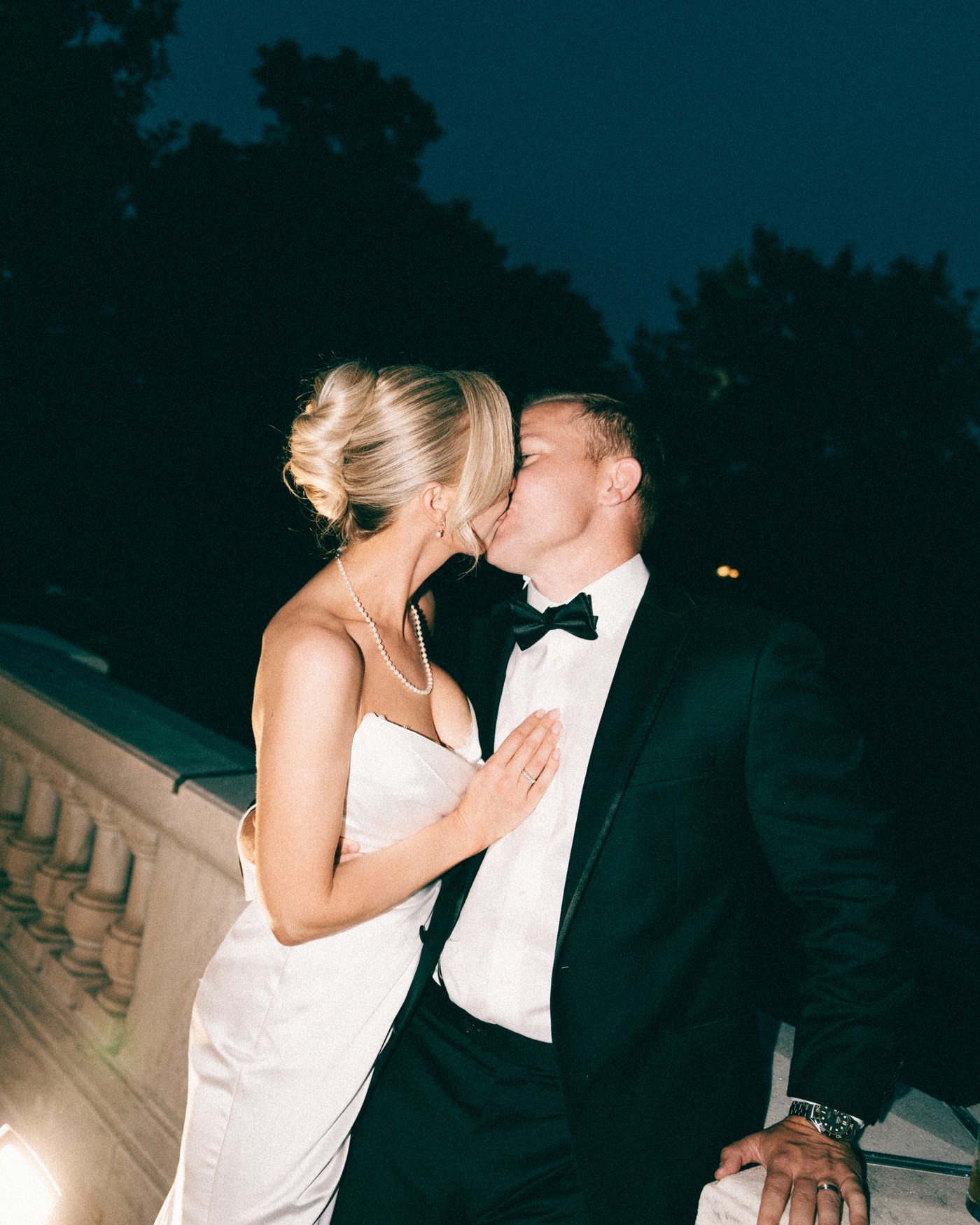 A couple kissing on a balustraded terrace after dark
