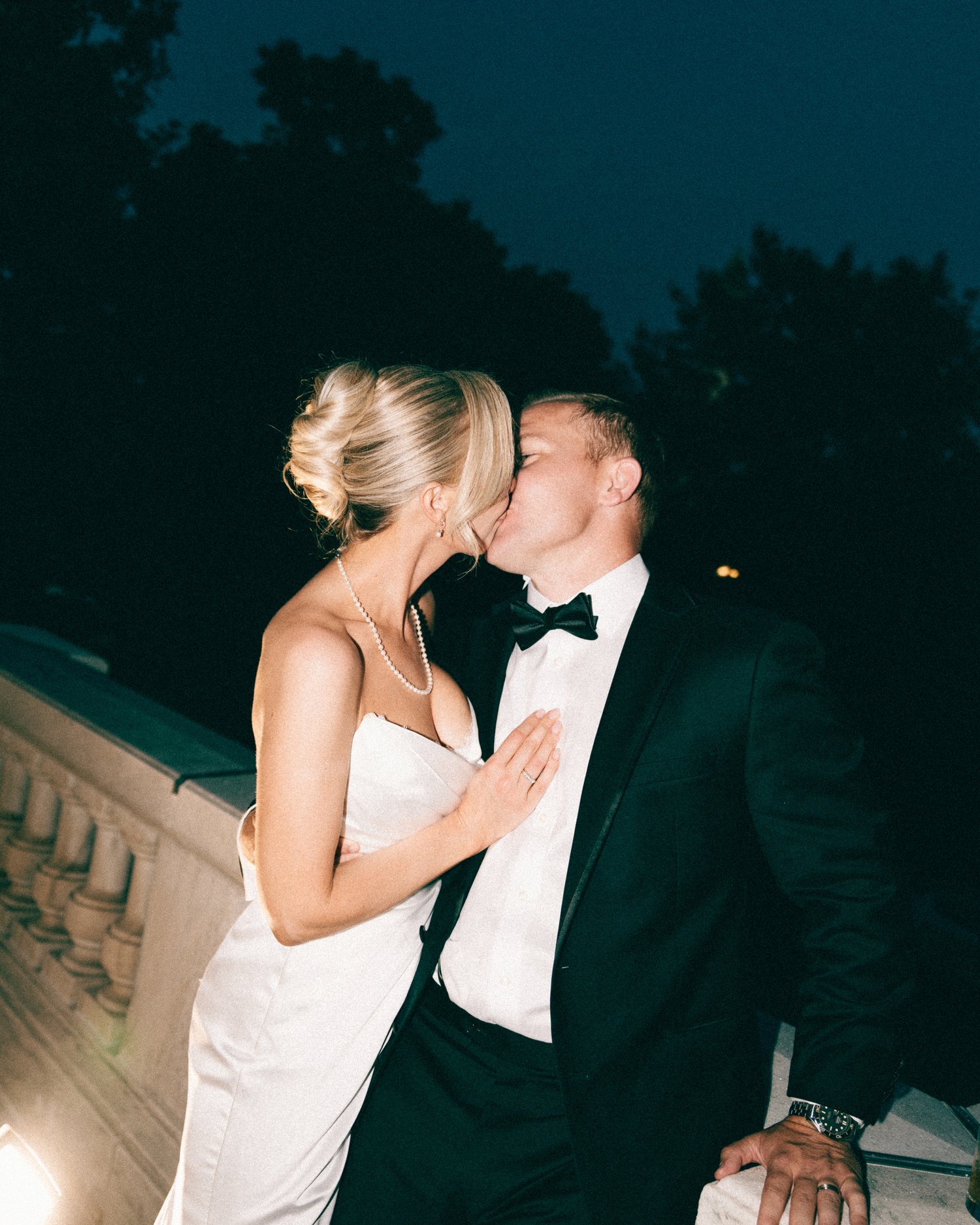 A couple kissing on a balustraded terrace after dark