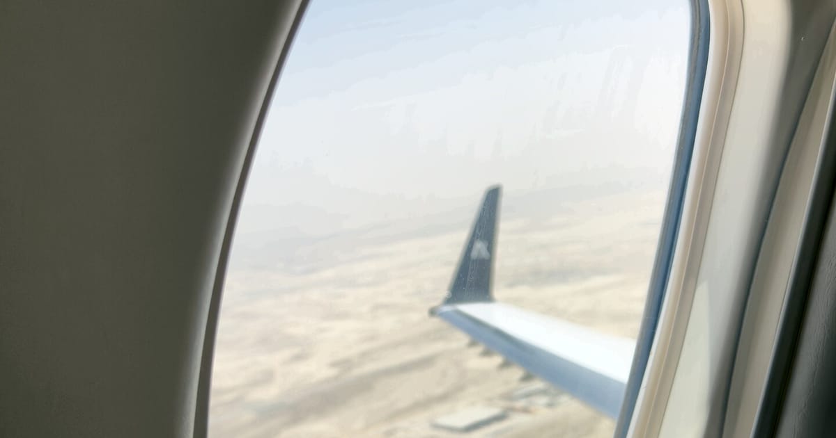 Wing over the desert through a private-jet cabin window
