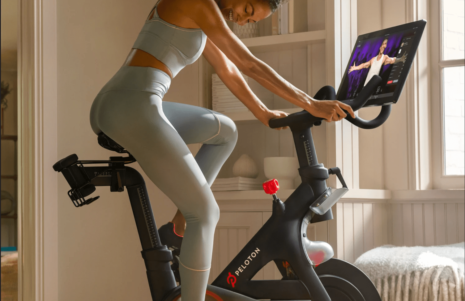 Woman riding Peloton Bike during live streaming class on screen