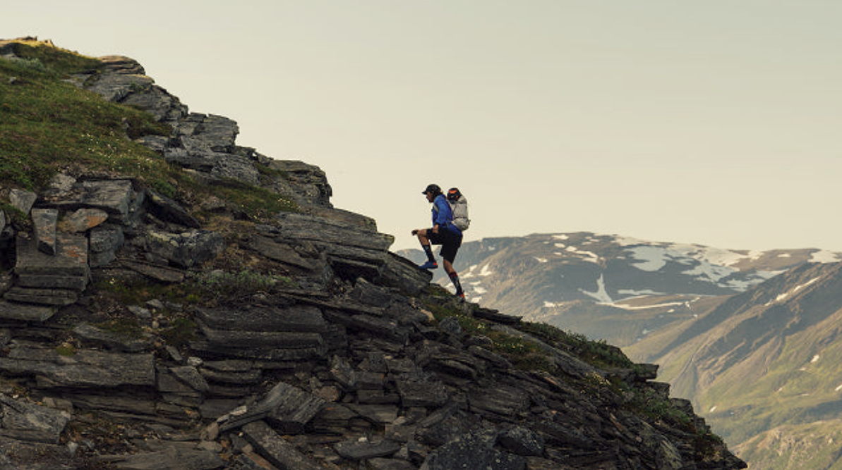  man ascending mountain ridge at high altitude