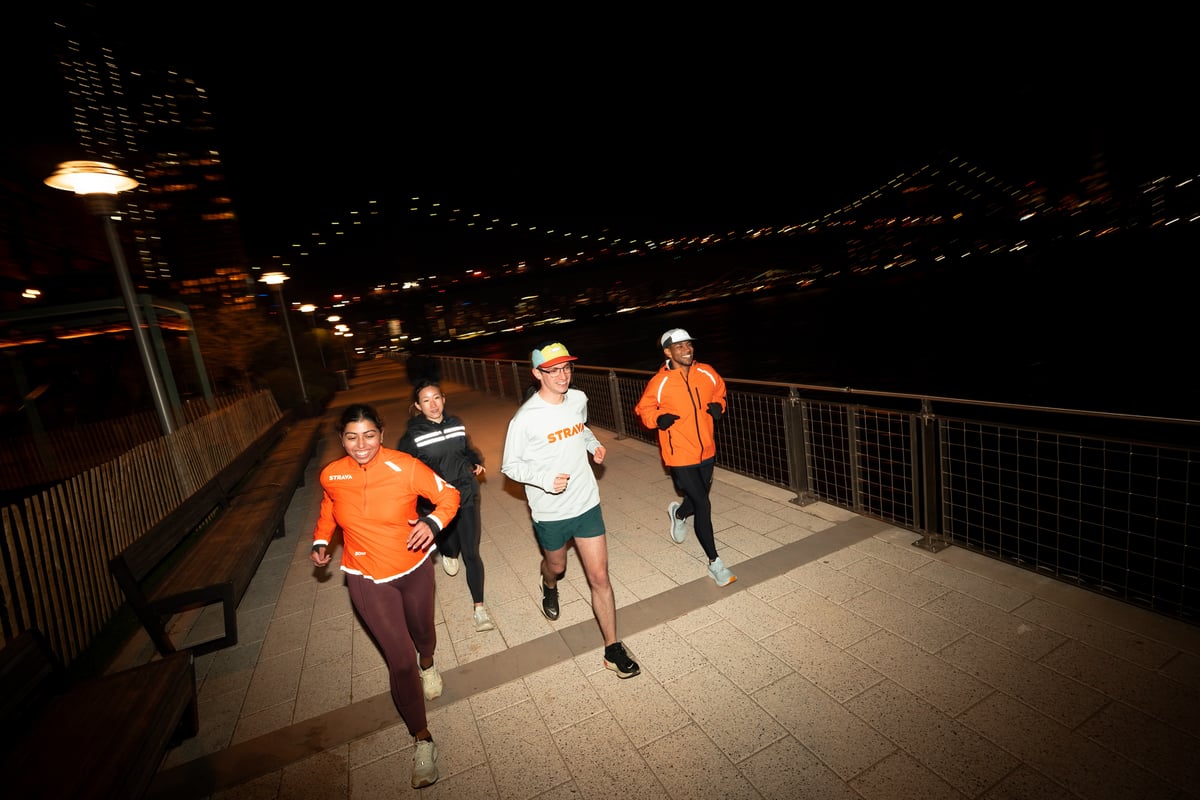 Group of runners at night wearing STRAVA running shirts