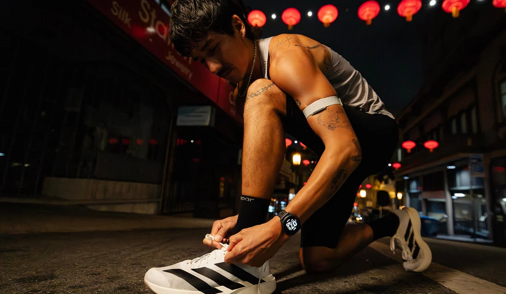 Close-up of COROS Pace 4 AMOLED screen while runner puts on shoes