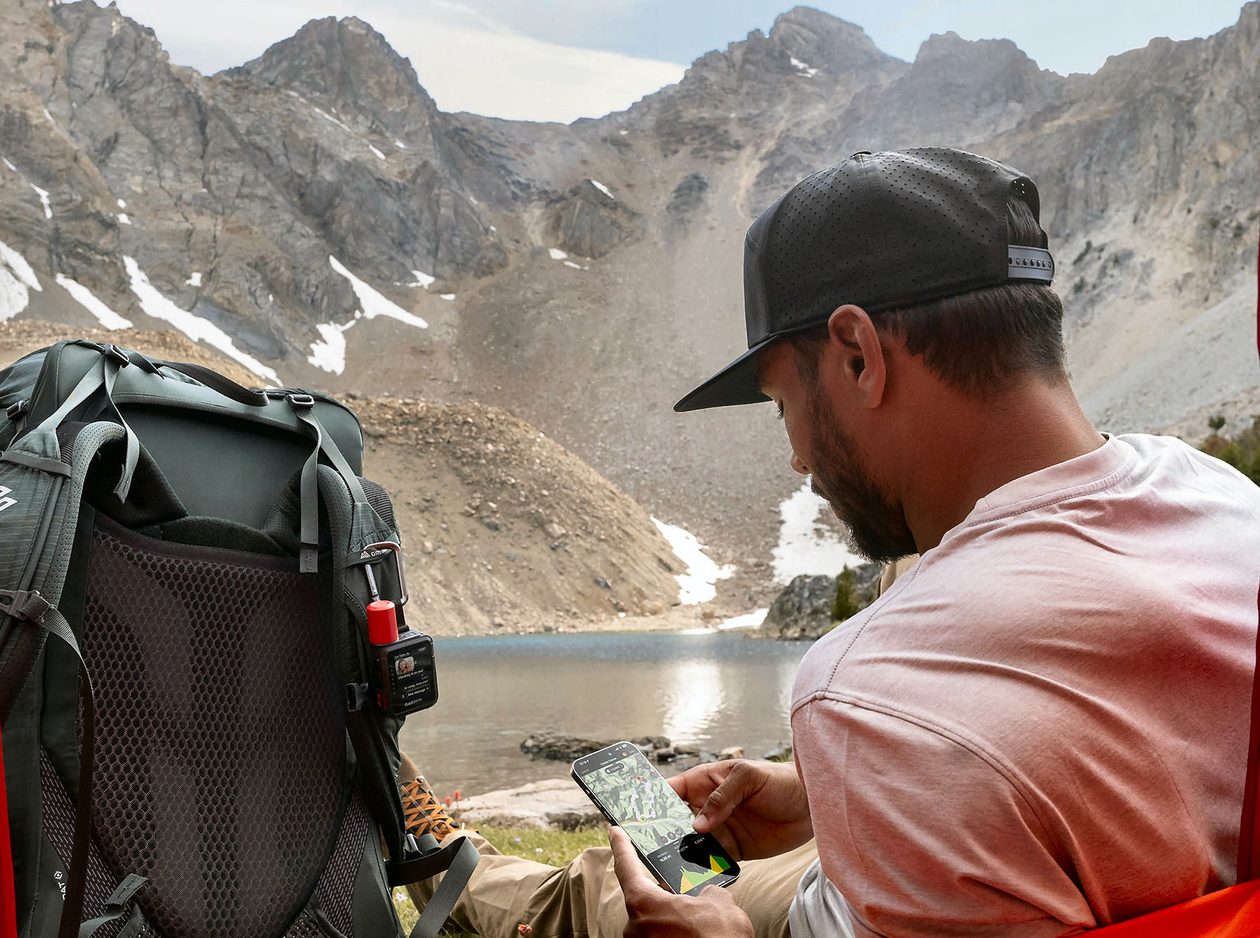 Man in mountains using a Garmin inReach Mini 3 Plus satellite communicator, illustrating the new multi-device support for Garmin's inReach ecosystem, including devices like the Fenix 8 Pro.