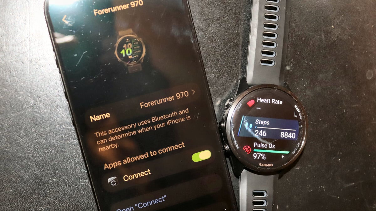armin Forerunner 970 next to iPhone showing Garmin Connect iOS background sync settings