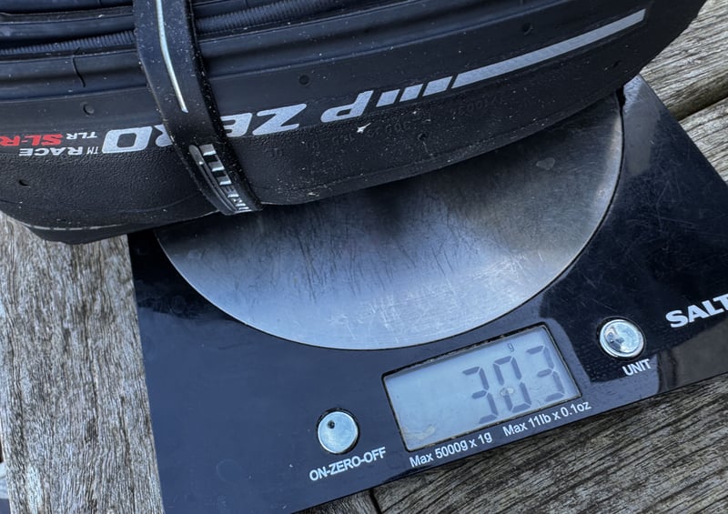 Pirelli P Zero Race TLR SL-R on scales showing measured weight of 303g