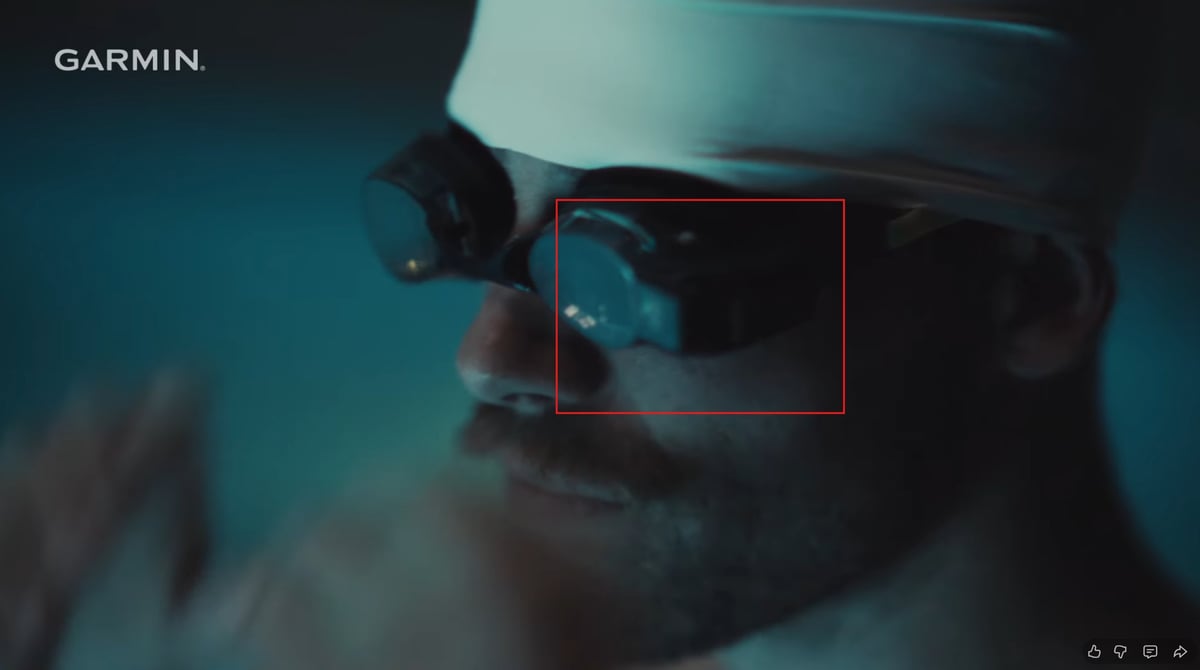 Garmin triathlon video still showing HUD-equipped swim goggles with left-side optical module