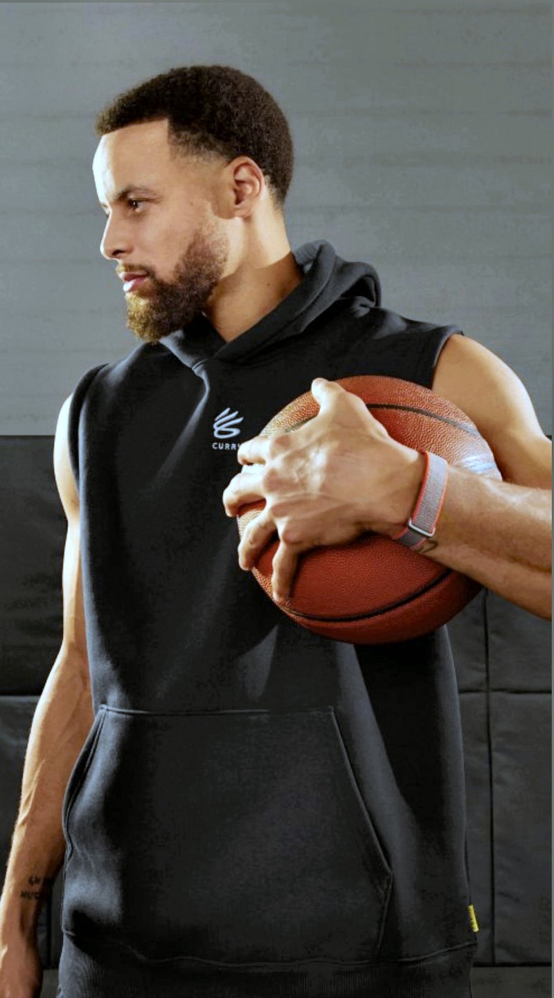 Steph Curry full wrist shot of Google's upcoming screenless Fitbit band with orange-accented clasp