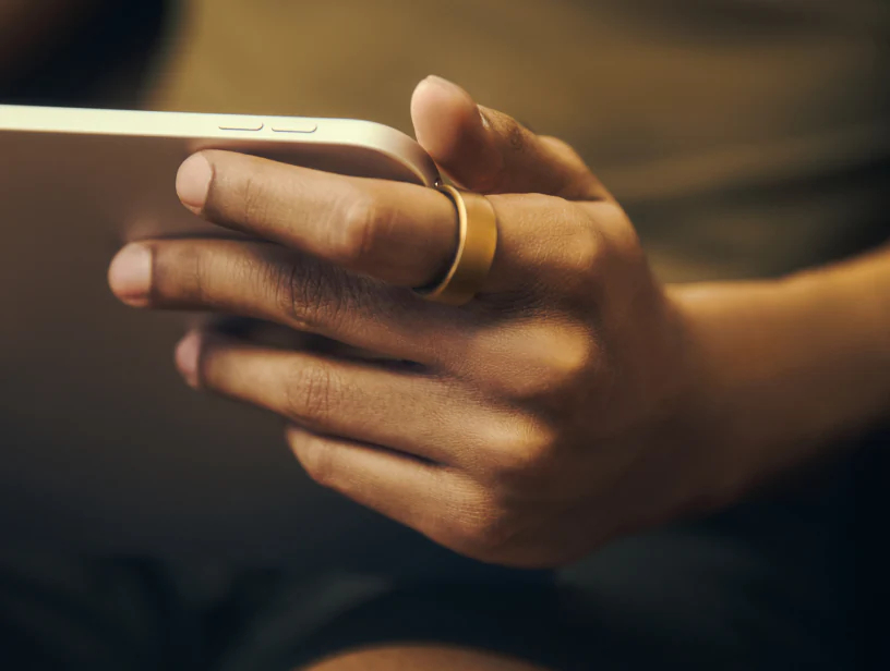 woman wearing a gold Ultrahuman Ring Pro while working on an iPad tablet