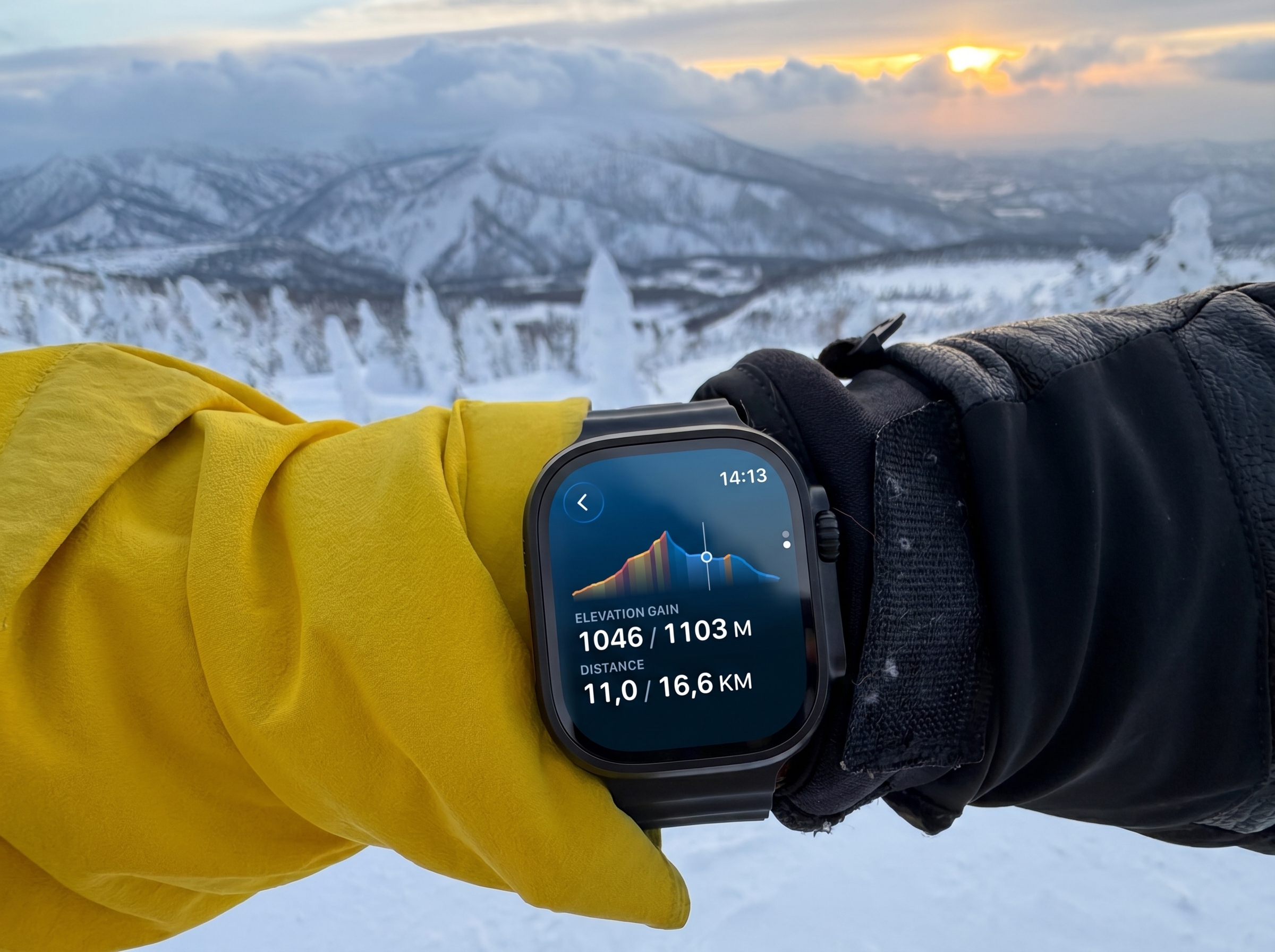 Route elevation profile on Apple Watch worn over winter clothing, snow and mountains behind