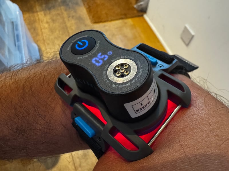Kineon MOVE+ pod strapped across a tennis elbow for 808nm laser therapy