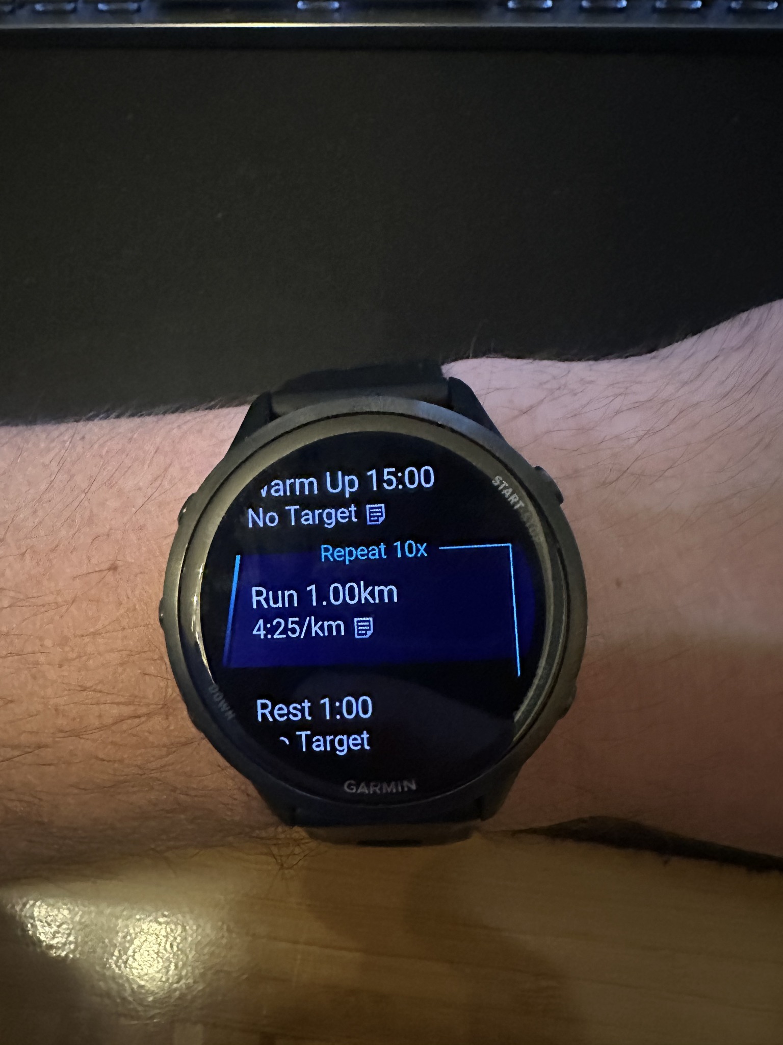 Garmin watch on Caleb Wetherell's wrist running the Norwegian 10 x 1K workout from Fit File Forge: repeat 10 times, 1.00 km at 4:25/km, rest 1:00