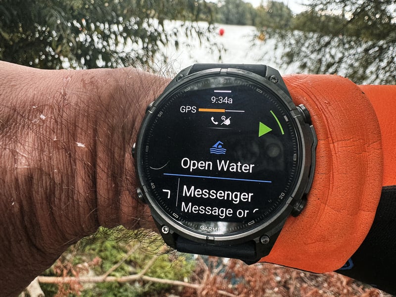 Garmin Fenix 9 Pro on a triathlete's wrist beside a wetsuit sleeve at Shepperton Lake