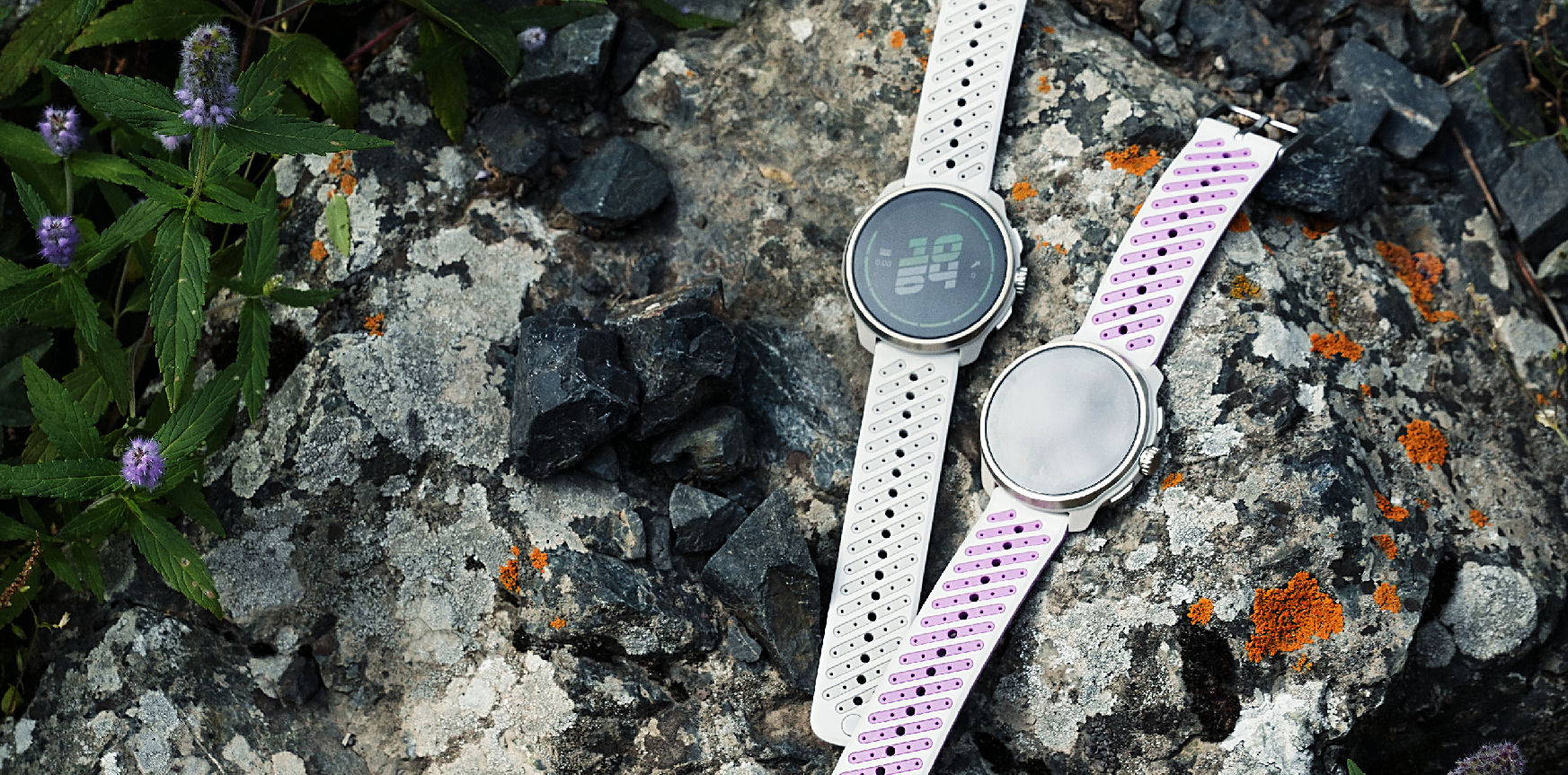 Two Suunto watches resting on a granite stone with orange lichen
