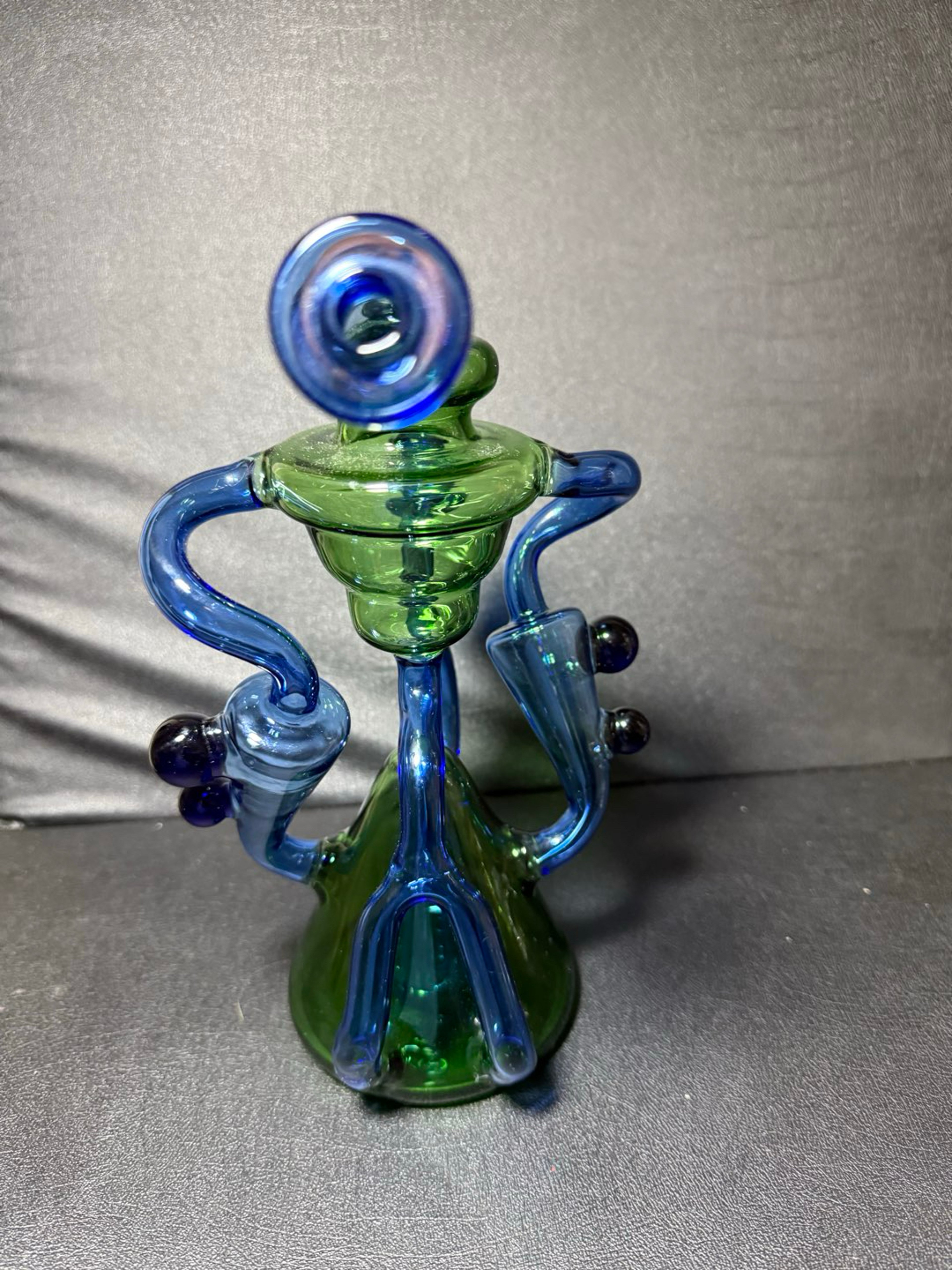 Preview pic of Beautiful 9.5” blue and green heady recycler featuring dual uptakes, single drain, super bent neck, excellent function, 14mm x 90 deg, inline perc with 6 slits