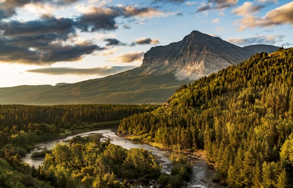 dramatic summer sunrise in Swift Current Lake in Many Glacier area in Glacier National park with the Grinnell Mt being illuminated by the sunrise .