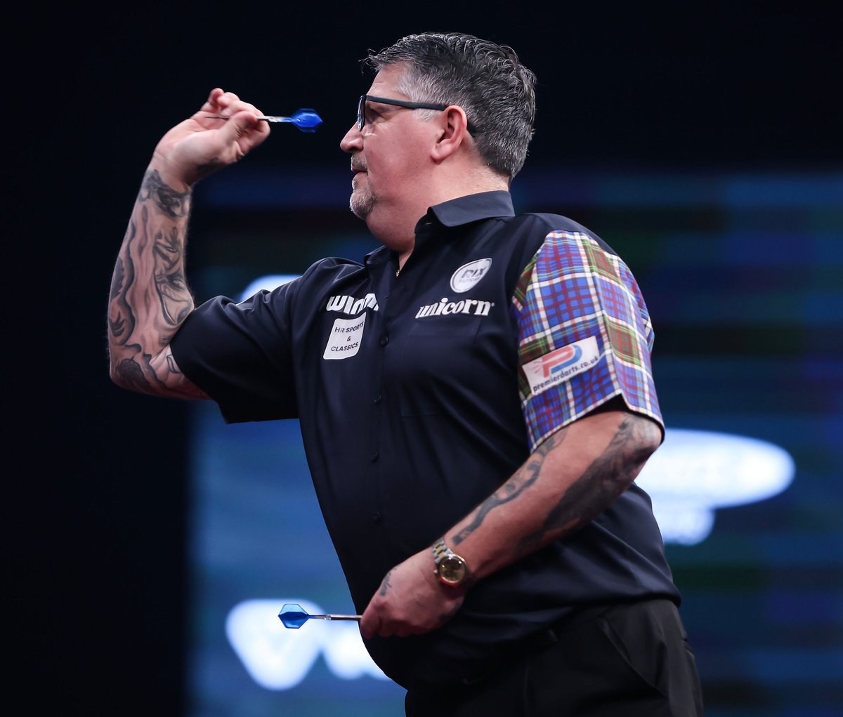 Gary Anderson holding a dart at eye level, showing his grip and aiming technique