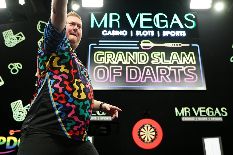 Ricky Evans celebrates on stage beneath the Mr Vegas Grand Slam of Darts sign at the 2025 tournament in Wolverhampton
