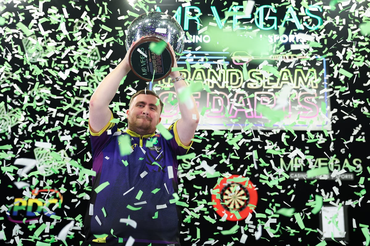 Luke Littler lifts the Eric Bristow Trophy in a shower of confetti after winning the 2025 Grand Slam of Darts