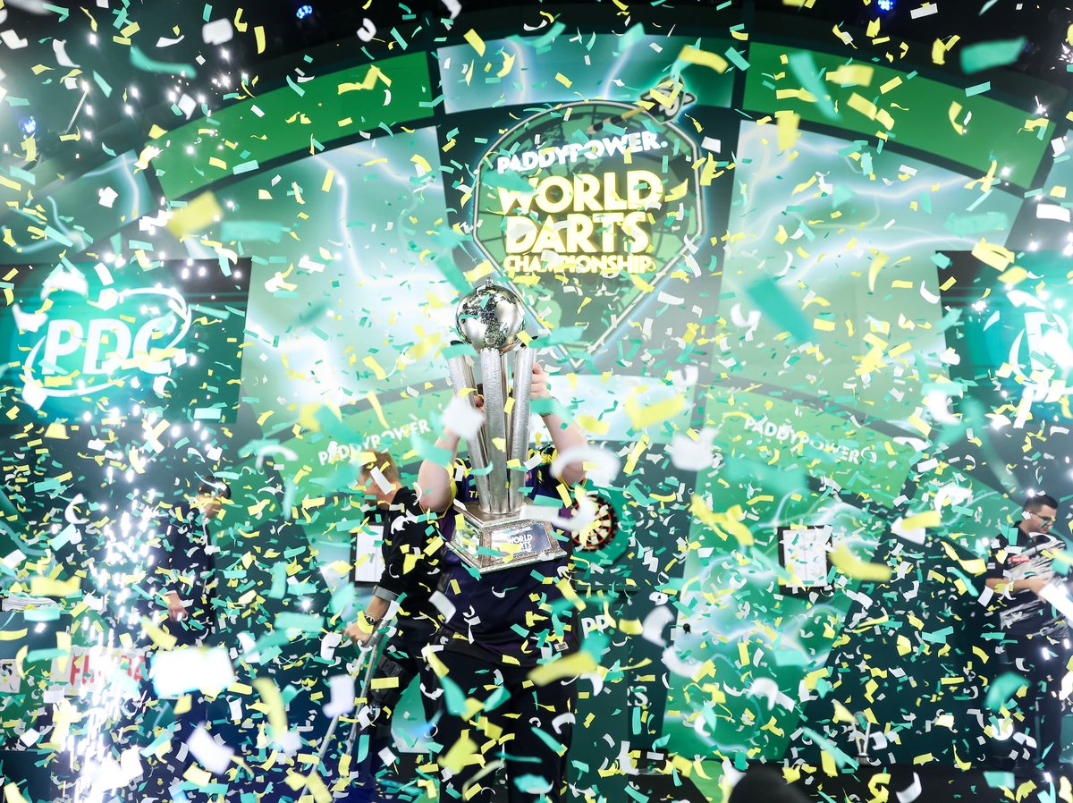 Luke Littler lifts the Sid Waddell Trophy through a shower of confetti after winning the 2026 World Darts Championship final
