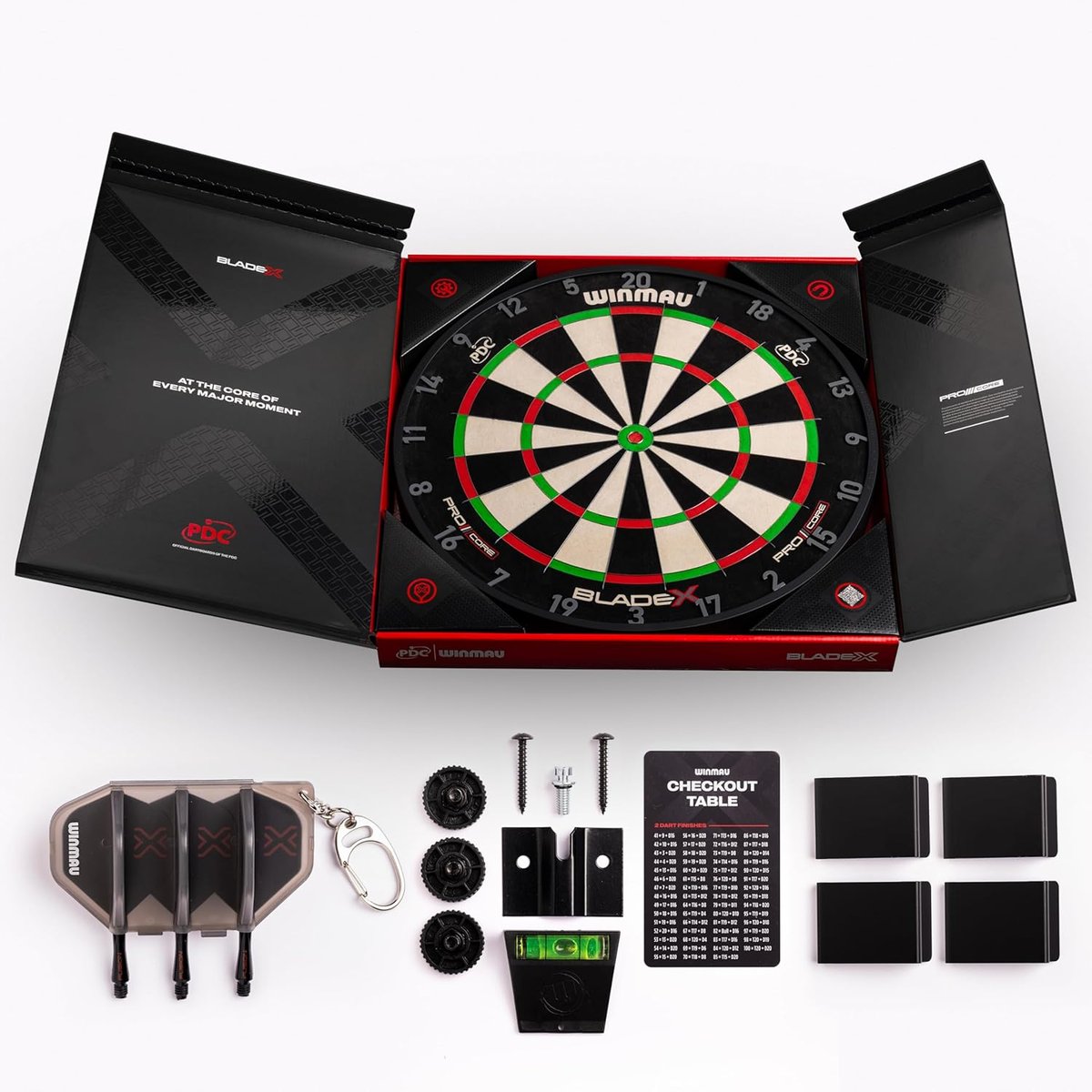 Winmau Blade X display box opened showing the dartboard, checkout card, spirit level, fixing kit, and accessories