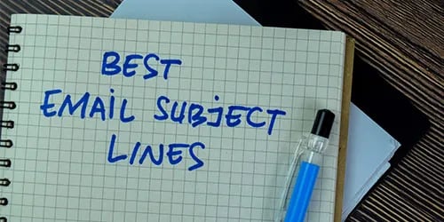 Photo of a lined notebook opened with "Best Email Subject Lines" written in blue ink. 