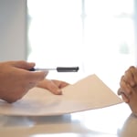 Opdrachtgever reikt een contract en pen aan om te ondertekenen