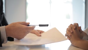 Opdrachtgever reikt een contract en pen aan om te ondertekenen