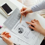 Twee collega's bekijken samen een onderzoeksrapport met cirkeldiagrammen en percentages